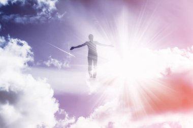 Bir adamın silüeti, gökyüzüne uçan, güneşten parlak ışınlarda, kollarını ayıran.