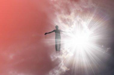 Bir adamın silüeti, gökyüzüne uçan, güneşten parlak ışınlarda, kollarını ayıran.