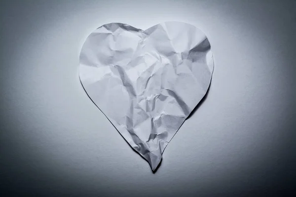 Символ сердца, сделанный из старой, скомканной бумаги на белом винтажном фоне. Символ разбитого сердца, несчастной любви . — стоковое фото
