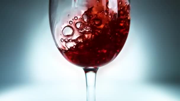 ガラスに注ぐ赤ワインの創造的なマクロスローモーションビデオ 赤ワインを注ぐガラスのクローズアップ — ストック動画