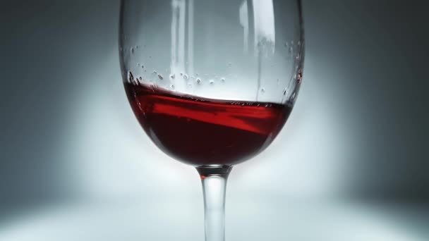 ガラスの中を波のように左右に飛び回る赤ワインの創造的なマクロスローモーションビデオ スパークリングワインとガラスのクローズアップ — ストック動画
