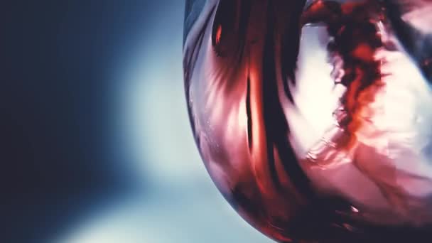 Kreatives Makro-Zeitlupenvideo von Rotwein, der in ein Glas gegossen wird. Glas mit einschenkendem Rotwein in Großaufnahme. Alter Retro Grunge Vintage Stil mit angenehmer, leichter und weicher Verfärbung.