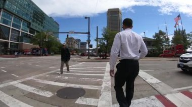 26 Eylül 2018. Baltimore, ABD. Kalabalık sokakta şehirde yürüyen insanlar. Yavaş hareket. Şehir siluetinin POV görünümü, gökdelenler ve Baltimore binaları. Şehir trafiği. Trafik geçen. 