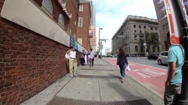 26 Eylül 2018. Baltimore, ABD. Kalabalık sokakta şehirde yürüyen insanlar. Yavaş hareket. Şehir siluetinin POV görünümü, gökdelenler ve Baltimore binaları. Şehir trafiği. Trafik geçen. 