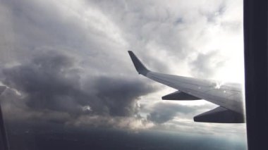 Uçak pencere görünümü. Hava seyahat. Airplane pencere koltuğundan görüntüleyin. Renkli gökyüzü ile bulutlar üzerinde uçan bir uçağın kanat. Uçak irtifa kazanır. Uçuş türbülans. Yavaş hareket.