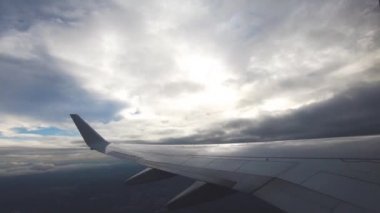Uçak pencere görünümü. Hava seyahat. Airplane pencere koltuğundan görüntüleyin. Renkli gökyüzü ile bulutlar üzerinde uçan bir uçağın kanat. Uçak irtifa kazanır. Uçuş türbülans. Yavaş hareket.