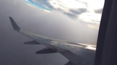 Uçak pencere görünümü. Hava seyahat. Airplane pencere koltuğundan görüntüleyin. Renkli gökyüzü ile bulutlar üzerinde uçan bir uçağın kanat. Uçak irtifa kazanır. Uçuş türbülans. Yavaş hareket.