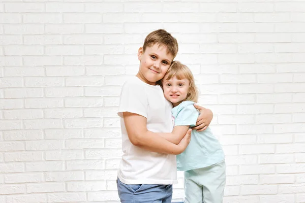 Bror och syster kramar mot tegel syster bakgrund — Stockfoto