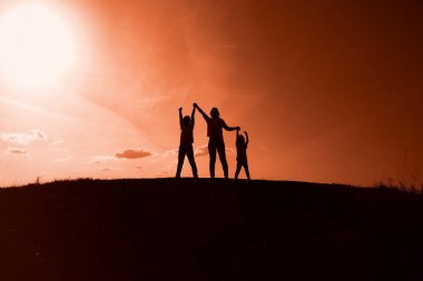 gün batımı arka planda anne, oğul ve kızı siluetleri