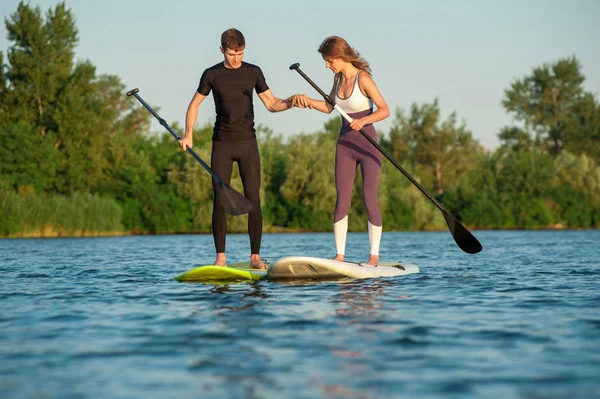 Happiness boy and girl on sup surf swimming at the river. Couple practicing