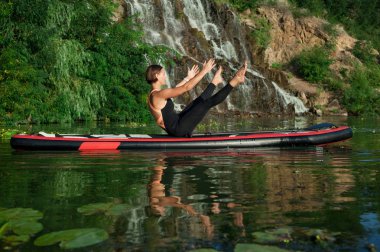 Sup paddleboarding adlı bir nehir üzerinde meditasyon genç güzel kadın