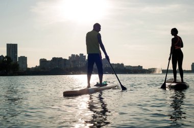 Plaj eğlenceli çift paddleboard, aşık bir çiftin güzel siluet ayağa üzerinde bir Web sitesi veya bilgisayar için duvar kağıtları