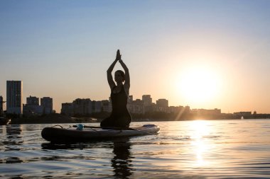 Şehir arka plan üzerinde yoga yapan bir ince kız silüeti