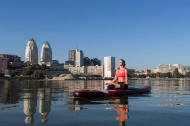 kürek kurulu yoga yoga su eğitim parlak şehir arka plan güzel kız tarafından gerçekleştirilen ayağa
