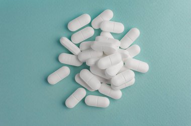Bir avuç turkuaz bir arka plan üzerinde beyaz hap