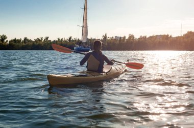 Kayık üzerinde canlı bir gün batımı sırasında kayak macera kadın. Şehir Dnepr alınan. Arkadan görünüm.