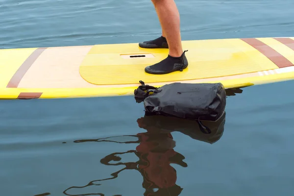 Foten Man Stående Gula Surfbräda Lugna Vatten Och Väska För — Stockfoto