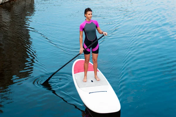 Menina atraente com corpo apto surf em stand up paddle board — Fotografia de Stock