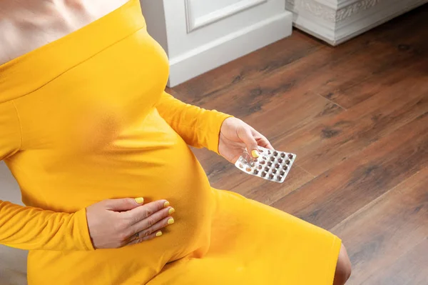 Беременная девушка думает, принимать ли таблетки — стоковое фото