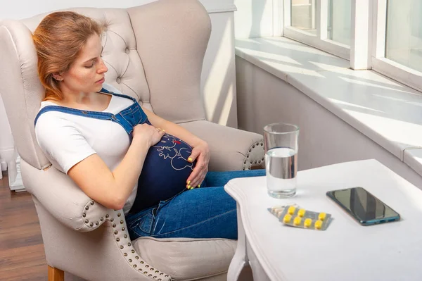 Enfermedad durante el embarazo. Mujer sentada en casa y tomando medicinas —  Fotos de Stock