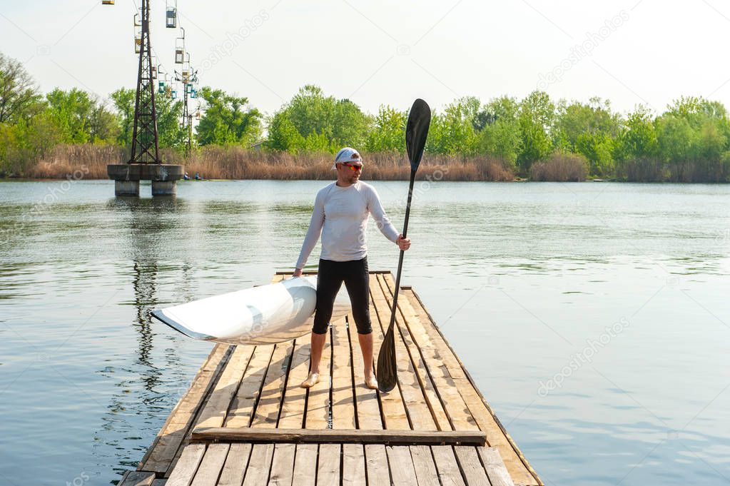 Man carrying kayak and oar after water sports at warm weather