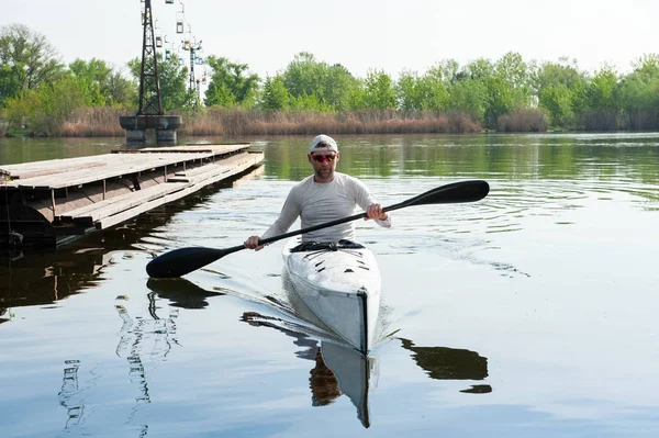 Hombre deportivo tranquilo sentado en canoa y sosteniendo la paleta —  Fotos de Stock