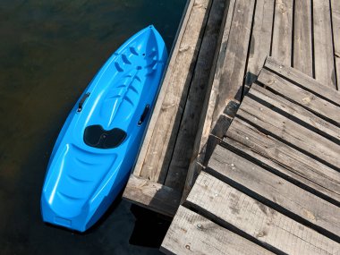Küçük plastik kürek teknesi Azure renk çocuklar için tasarlanmıştır. Tahta Pier yakınında Kano üst görünümü fotoğrafı
