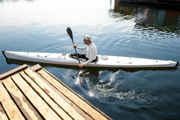 Active hobby concept. New white canoe with paddle man departing from the pier