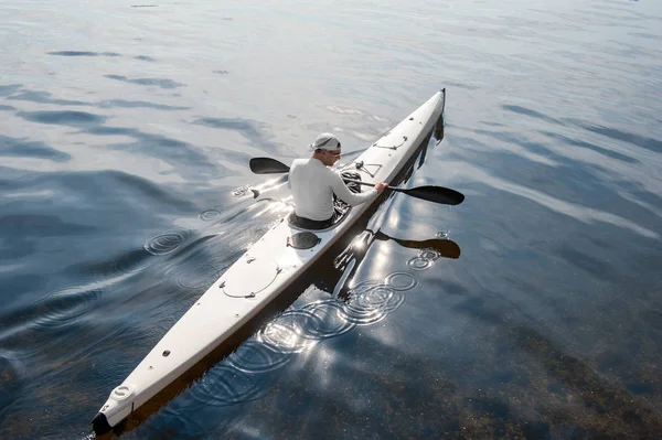 Aerial view of middle aged man rowing sportive canoe in quiet water in sunny warm weather