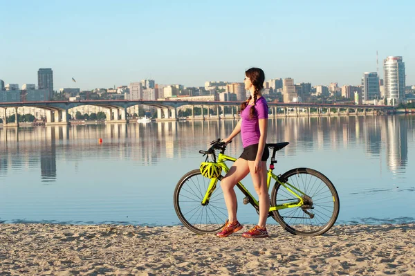 Ön planda sportif kız ve bisiklet ile açık sabah panoramik şehir manzarası