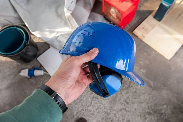 一名男性建筑工人手持建筑用头盔和耳机 没有噪音 后续行动 图库照片
