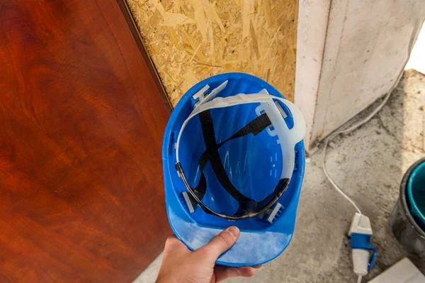 公寓维修安全概念 一个工人正准备戴上蓝色的头盔 图库图片