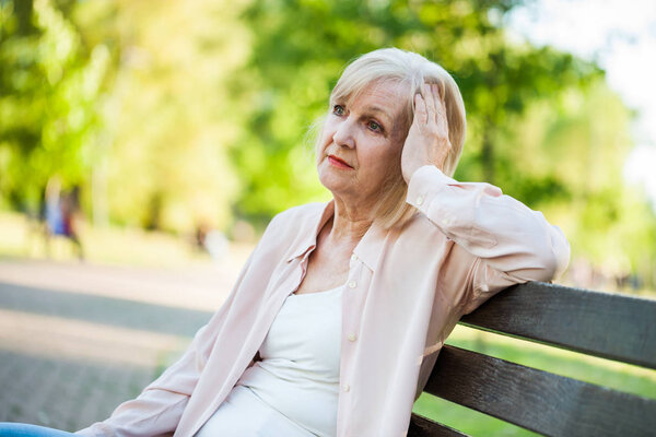 Lonely adult woman sitting in park in despair. 