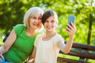 Büyükanne ve torunu parkta oturan ve selfie alarak. 