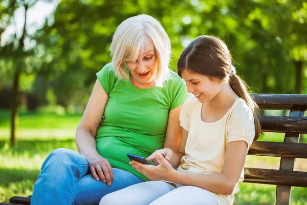 Nagymama Unokája Parkban Mobiltelefon Használata — Stock Fotó