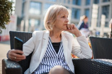 Üst düzey işkadını kafede oturan ve smartphone kullanarak.