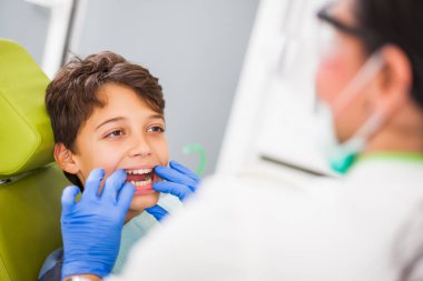 Dişçi bir çocuğun dişlerini inceliyor.. 