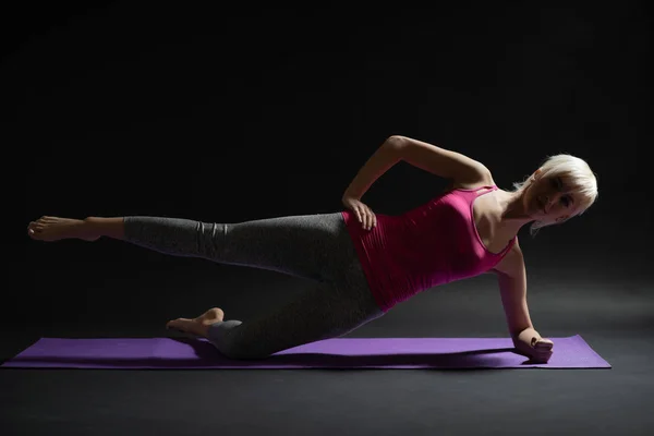 Woman exercising pilates. Side plank with leg kick exercise.