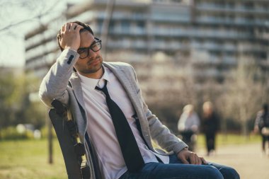 Genç yorgun işadamı parkta işten sonra dinleniyor.