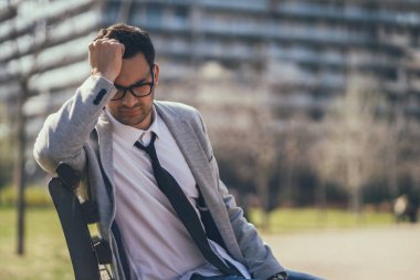 Genç işadamı kovulduktan sonra parkta oturuyor. Depresyona girmiş..