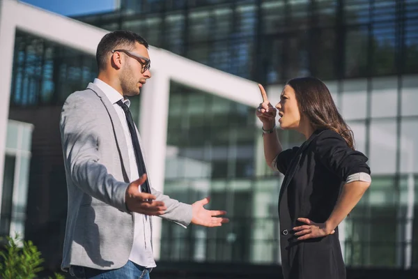 Business colleagues are arguing outside the company building.