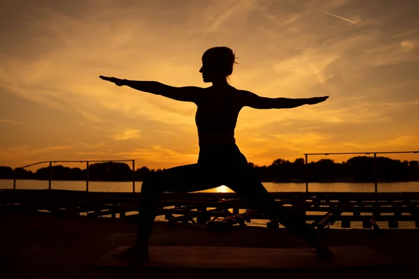 女人在日落时练习瑜伽 维拉巴德拉萨纳 — 图库照片