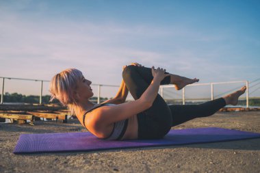 Güneşli bir günde pilates uygulayan kadın. Tek düz bacak germe egzersizi.