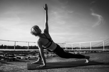 Güneşli bir günde yoga yapan kadın. Virabhadrasana, Döndürülmüş savaşçı pozu 