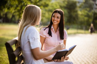 İki iş arkadaşı parkta oturup konuşuyorlar..