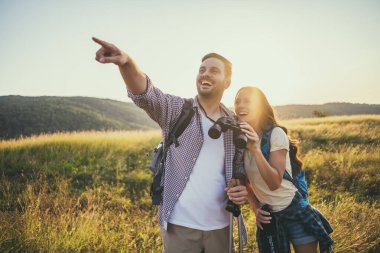 Mutlu çift dağda yürüyüş yapıyor. Doğayı dürbünle izliyorlar..