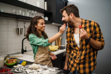 Mutfakta yemek yapan çok ırklı mutlu çift. Kurabiye yapıyorlar..