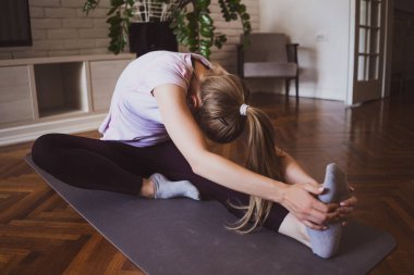 Evde pilates ve yoga egzersizleri yapan genç bir kadın..