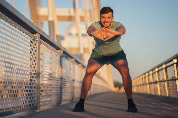这个年轻人正在城市的桥上锻炼 — 图库照片