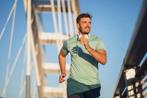 若い男が街の橋の上で屋外でジョギングしている — ストック写真